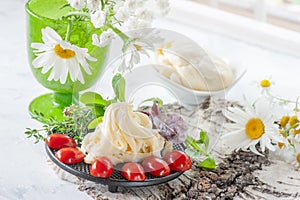 Traditional white soft fibrous Cecil cheese lies on a plate. The cheese is decorated with ripe tomatoes and gooseberries