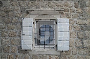 Traditional white wooden open window shutters on stone home