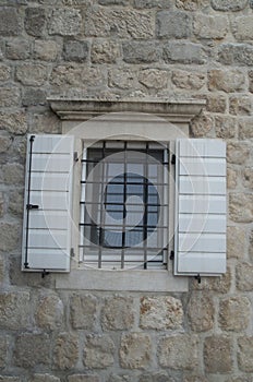 Traditional white wooden open window shutters on stone home