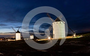 Traditional whitewshed Spanish windmills in La Mancha under a dark blue night sky