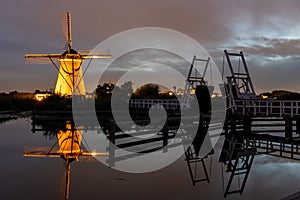 Traditional windmills and open drawbridge in night sky at Kinderdijk