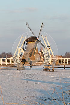 Traditional windmills with skater on ice and open drawbridge Kinderdijk, Netherlands
