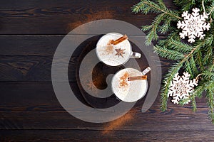 Traditional winter eggnog on dark wooden background. Drink with grated nutmeg, milk, whipped eggs, cinnamon