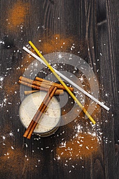 Traditional winter eggnog with milk, rum and cinnamon, sprinkle with grated nutmeg. Cocktail straws, dark wooden background