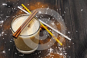 Traditional winter eggnog with milk, rum and cinnamon, sprinkle with grated nutmeg. Cocktail straws, dark wooden background