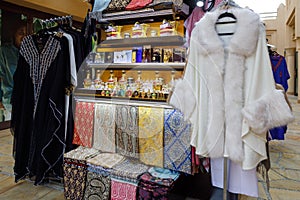 Traditional womens abaya, neckerchiefs, perfumes and furs on the counter of a street shop