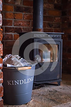 Traditional Wood Burning Stove in a Red Brick Hearth With A Basket of Kindling in the Foreground