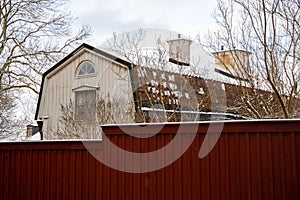 Traditional wooden architecture of Sweden. White wooden house with a brown tiles roof and dark red fence.