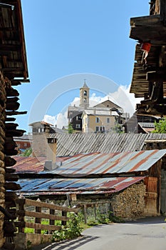 Traditional wooden balconies and roofs with the church in the background in Saint Veran village