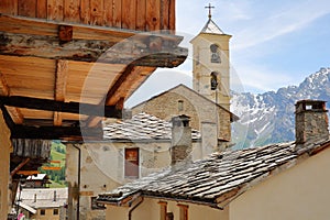 Traditional wooden balconies and roofs with the church in the background in Saint Veran village