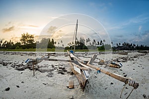 Sunset on the tropical beach with traditional wood boat, palm trees and white sand in Diani beach, Watamu Kenya and Zanzibar, Tanz