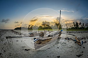 Sunset on the tropical beach with traditional wood boat, palm trees and white sand in Diani beach, Watamu Kenya and Zanzibar, Tanz