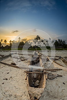 Sunset on the tropical beach with traditional wood boat, palm trees and white sand in Diani beach, Watamu Kenya and Zanzibar, Tanz
