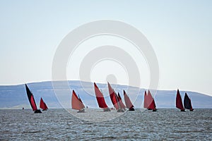 Traditional wooden boats with red sail.