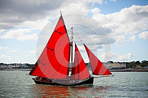 Traditional wooden boats with red sail.
