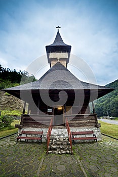 Traditional wooden church in the mountains against a cloudy sky