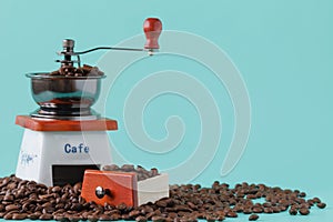 Traditional wooden coffee mill grinder over aquamarine background