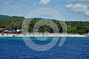 Traditional wooden fishing boats on a beach with green palms and blue water