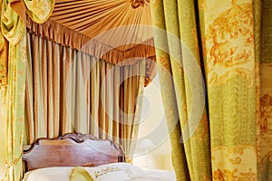 Traditional wooden four poster bed with drapes and curtains