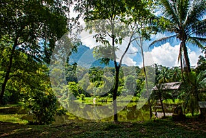 Traditional wooden house near the lake and mountain in the background. Kuching to Sarawak Culture village. Borneo, Malaysia