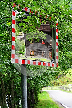 Traditional wooden house reflected in a roadside convex safety mirror near Heiligenblut am Grossglockner, Austria.