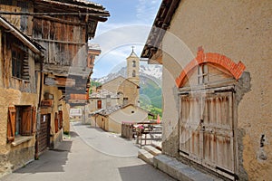 Traditional wooden houses and the church in Saint Veran village, with mountain range covered with snow in the background photo