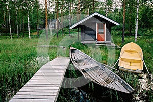Traditional wooden hut. Finnish sauna on the lake and pier with fishing boats