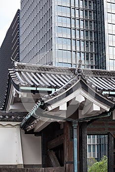 Traditional wooden Japanese tile roofs against contemporary glass and metal sky scrapers are in center of Tokyo city, Japan