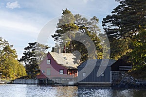 Traditional wooden Norwegian houses surrounded by trees and near the sea