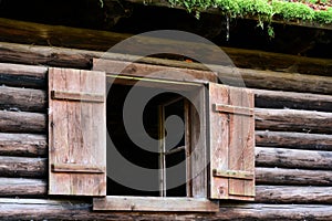 Traditional wooden open shutters on the window of an old wooden log house. Architectural heritage