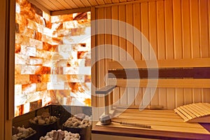 Traditional wooden sauna. Classic interior. Empty seats, bucket lies. Stone brick wall lighting. Heat stones