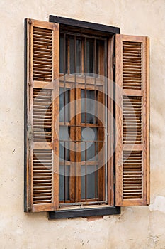Traditional wooden shuttered window in Neve Tzedek, Tel Aviv-Yafo, with iron bars and textured stucco wall, showcasing classic photo