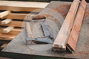 Traditional woodworking using old and hand tools such as an axe and planer stored on an iron table with wooden logs