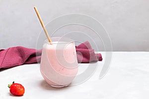 Traditional yogurt indian drink Strawberry Lassi in a glass cup on concrete neutral background