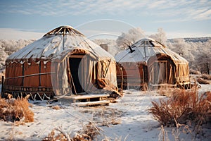 Traditional yurts set against a frosty winter backdrop with sunlit trees.