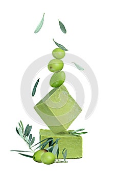 Traditionalhandmade organic olive soap. Soap bars balanced on one another, green olives and falling olive leaves isolated on white