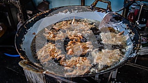 Traditionally battered shrimp are being fried in hot oil on a pan to be sold as food