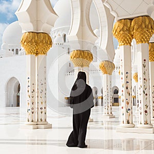 Traditionally dressed arabic woman wearing black burka wisiting Sheikh Zayed Grand Mosque in Abu Dhabi, United Arab