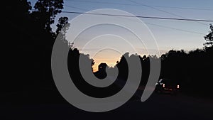 Traffic at a 4 way stop in the country at sunset truck and car tail lights