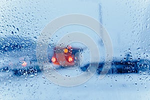 Traffic abstract in winter. Traffic seen from inside a car. Water drops on windshield and car tail lights in bokeh