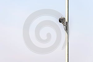 Traffic camera on metal pole over bright sky background in british town