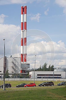 Traffic, cars and a green lawn against the background of a thermal power plant, heating in the city, urbanism.