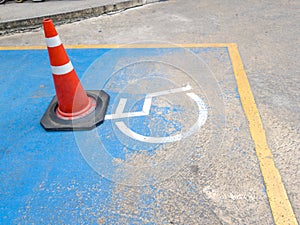 Traffic cone on Disabled parking. International Symbol of painted in bright blue on center parking space. Facilitates the provisio