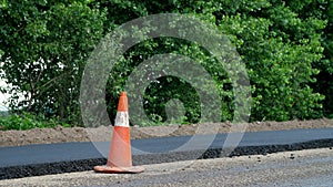 Traffic Cone on road. Road construction works , road repair. On the road there is fresh asphalt laid on one side of the