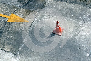 Traffic cone on the road with yellow arrow on the ground
