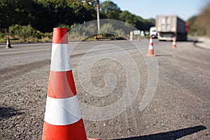 Traffic cone, with white and orange stripes on gray asphalt, copy space