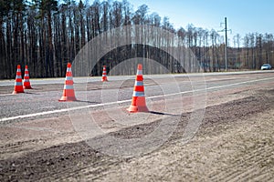 Traffic cones were installed on the roadway. Road works in the spring. Construction cone or road cone. Safety pylon, with white