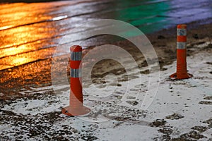 Traffic cones at winter night city with snow and footprints