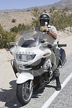 Traffic Cop Monitoring Speed Though Radar Gun