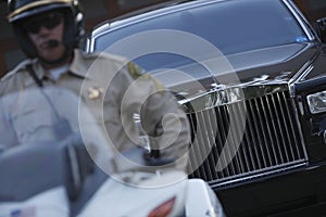 Traffic Cop Sitting On Motorbike With Car In Background